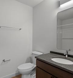A bathroom with a toilet, sink, and mirror.
