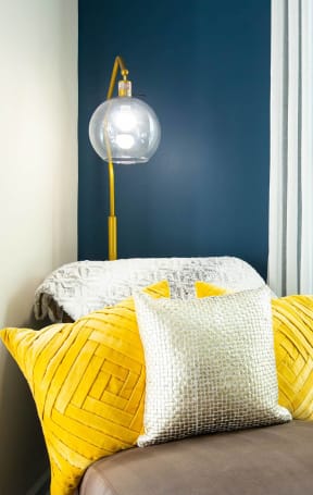 a small bedroom with a bed with yellow pillows and a lamp