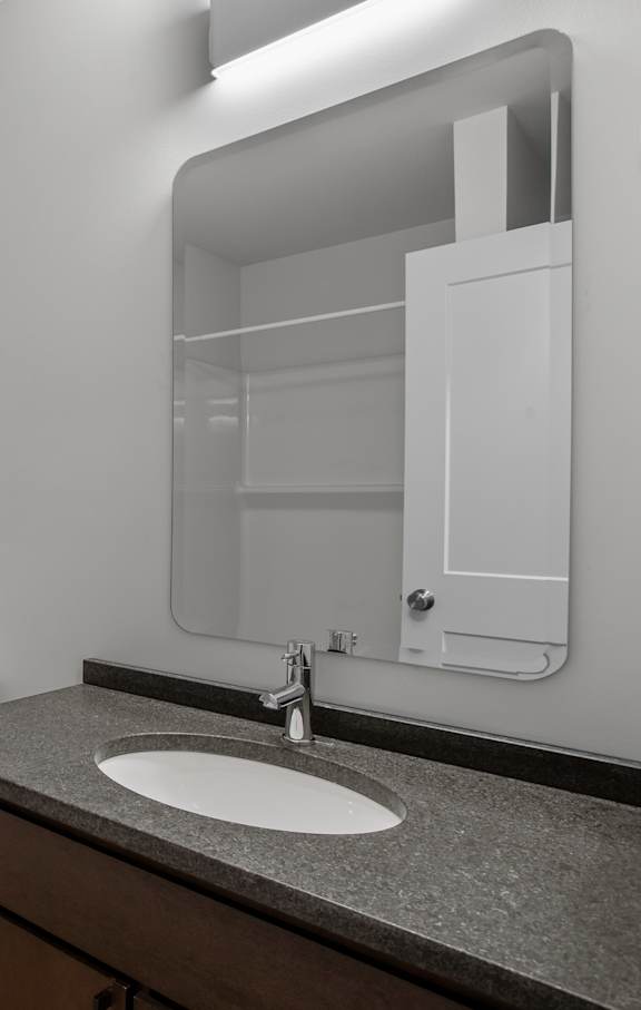 A bathroom with a toilet, sink, and mirror.
