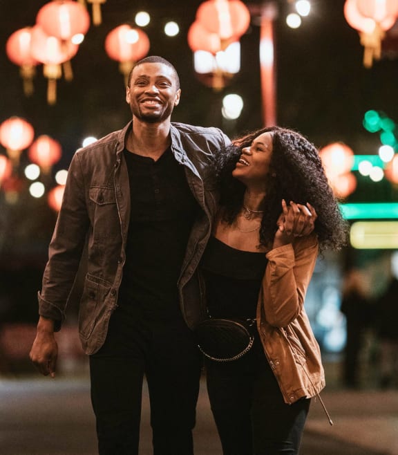 a man and a woman walking down a city street at night
