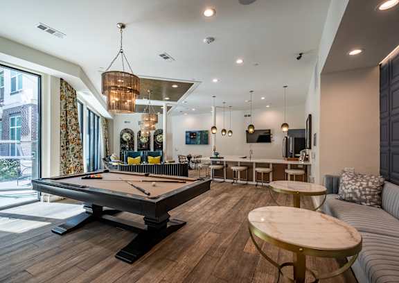 A pool table is in the middle of a room with a couch and a table.