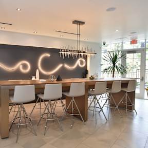 A modern kitchen with a large island and white chairs. at 360 Luxury Apartments, San Diego, CA, 92122