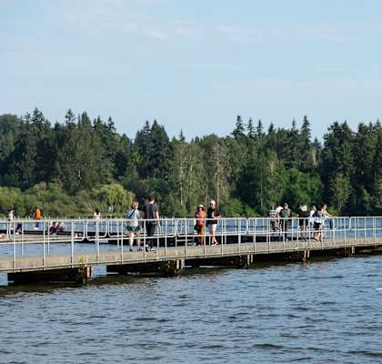 People are kayaking on a lake with a dock in the background.