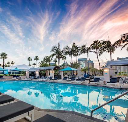 A pool with lounge chairs and palm trees in the background. at Towers at Costa Verde Apartments, San Diego, CA
