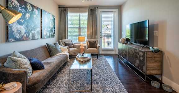 A living room with a brown couch, a coffee table, and a television.