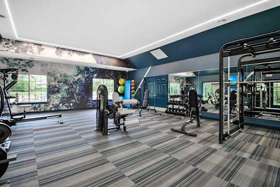 A gym with a variety of equipment including treadmills, weights, and exercise machines.