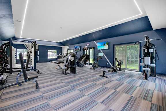 A gym with a variety of equipment including treadmills, weights, and exercise machines.