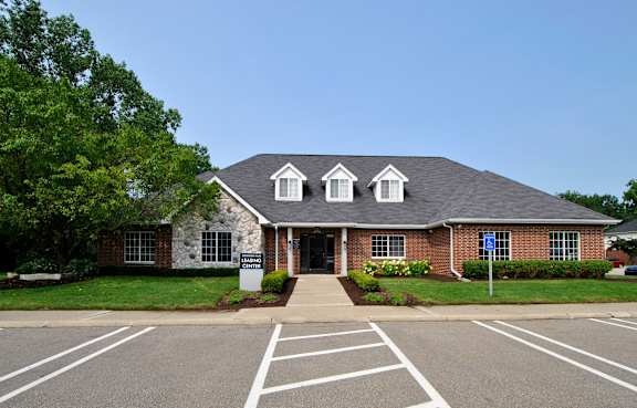 A brick building with a white roof and a tree in front.