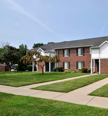 A brick house with a white roof and a tree in front.