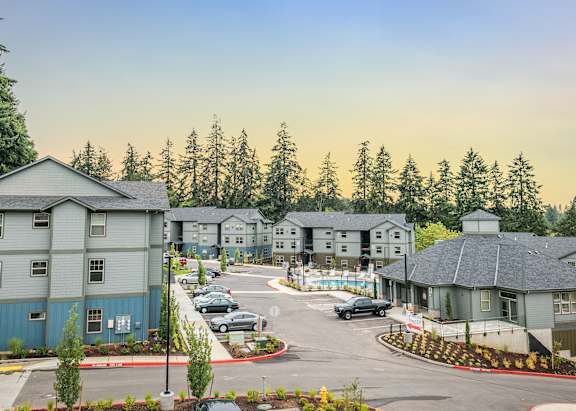 A view of a housing complex with a parking lot in front.