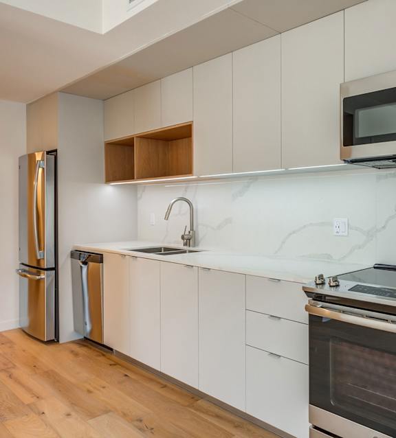 A kitchen with a stainless steel refrigerator, microwave, oven, and sink.