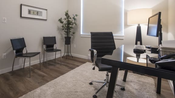 an office with a desk and chairs and a large window