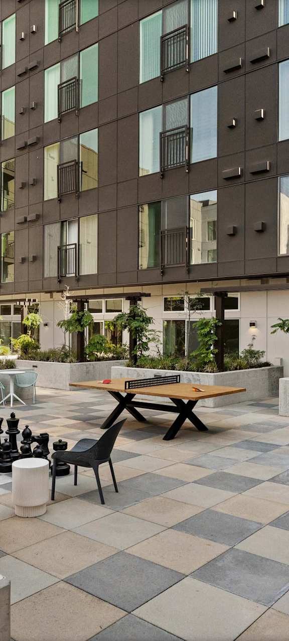 A courtyard with a checkerboard patterned floor and a variety of chairs and tables.