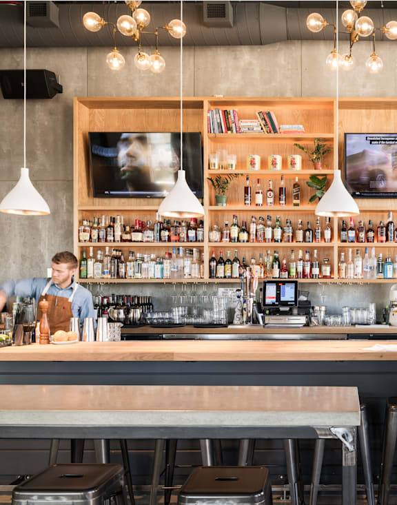 A man is sitting at a bar with a bartender behind the counter.