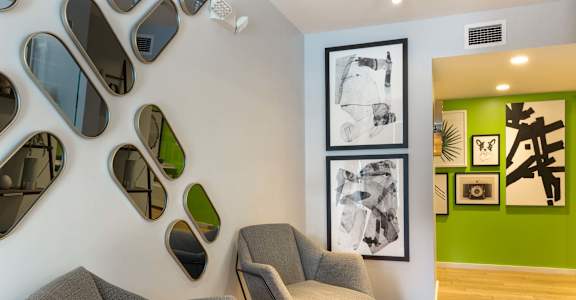 A living room with a grey couch and a green wall.