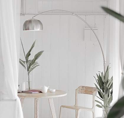 A white chair sits next to a white table with a plant on it.