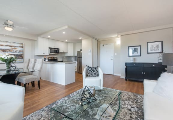 a living room and kitchen with white furniture and a glass table