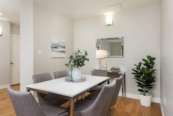 a dining room with a white table and chairs and a mirror