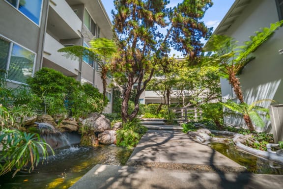 a courtyard with a water feature and trees in front of a building  at Sunset Barrington Gardens, Los Angeles, California