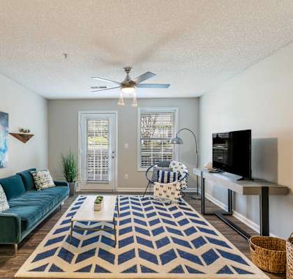 A living room with a blue couch and a rug.