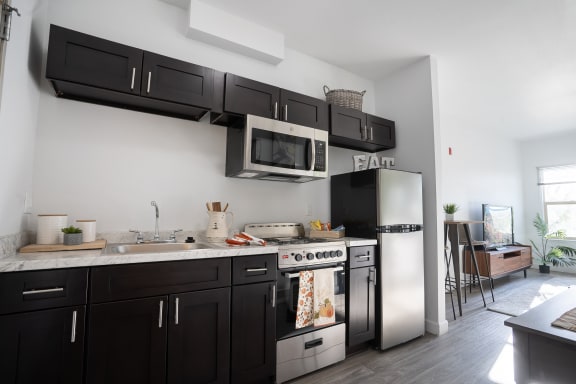 A modern kitchen with black cabinets and stainless steel appliances. at ParcOne60, Reno, 89501