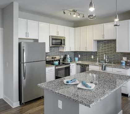 A kitchen with a granite countertop and stainless steel appliances.