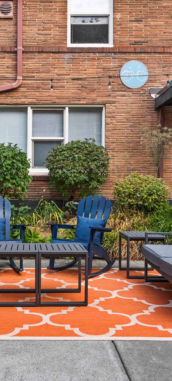 A patio with a table and chairs in front of a brick building.