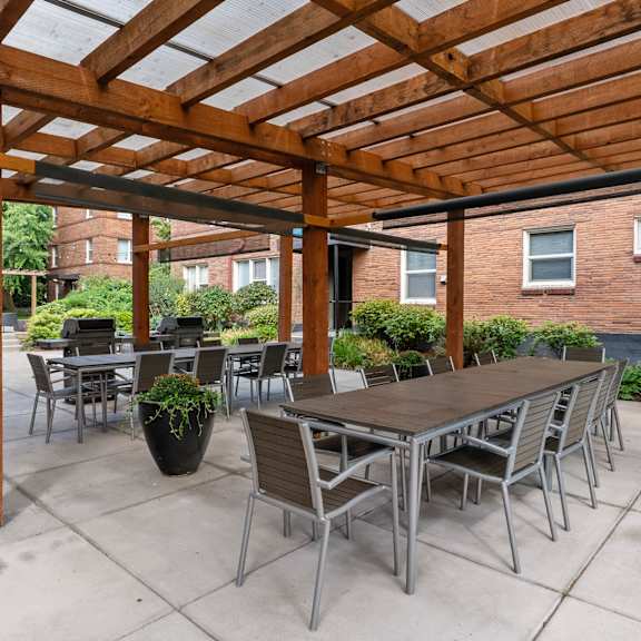 A wooden pergola with a table and chairs underneath.