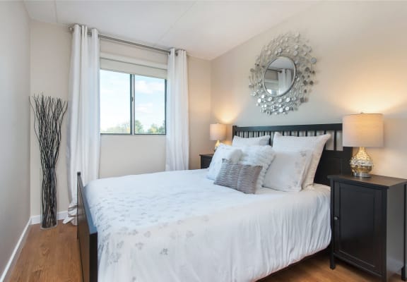 a bedroom with a white bed and a mirror