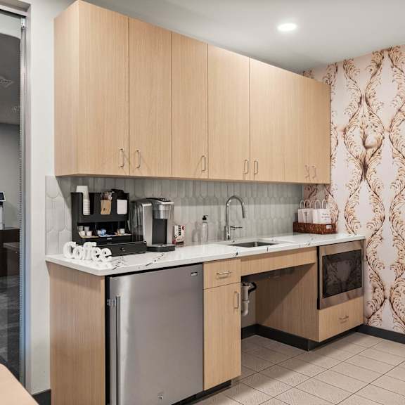A kitchen with wooden cabinets and a patterned wallpaper.