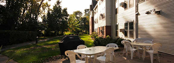 A patio with a white table and chairs is set up outside a building.
