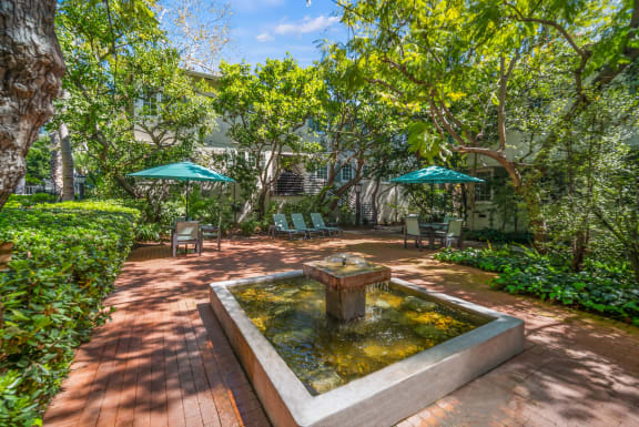 a courtyard with a fountain and a patio with umbrellas at Sunset Barrington Gardens, Los Angeles, CA, 90049