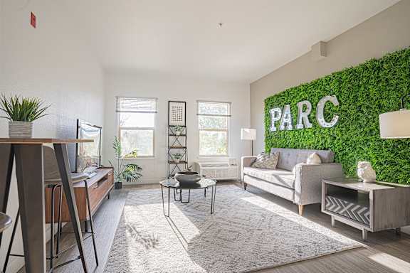 A living room with a green plant wall and a white rug.