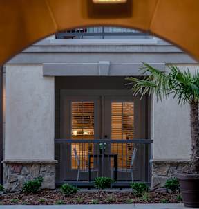 a door to a building with a palm tree in front of it at The Villa at River Pointe, Maumelle, AR 72213