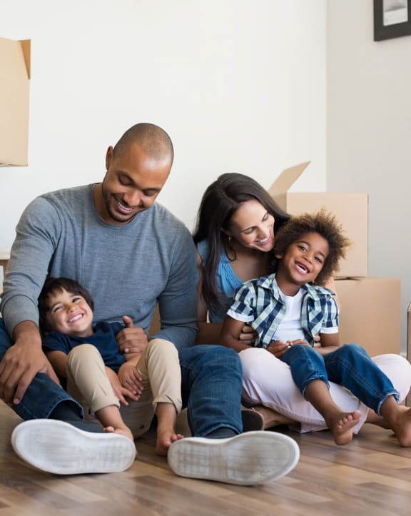 a family sitting on the floor in their new home  at Pinnacle Apartments, Jacksonville, FL, 32256