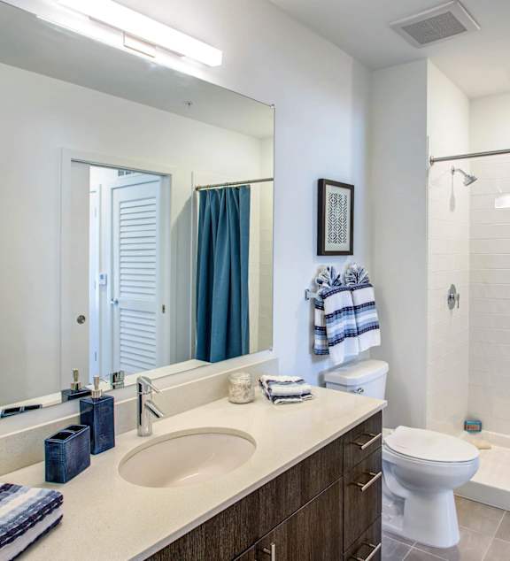 A bathroom with a white toilet, sink, and shower.