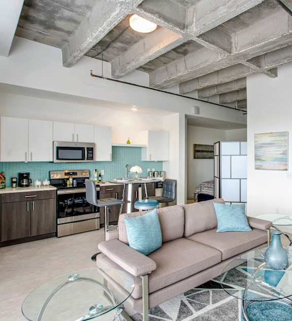 A modern living room with a glass coffee table and a grey couch.