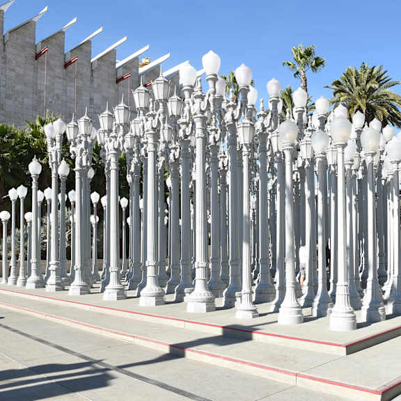 A row of white street lamps are lined up on a sidewalk.