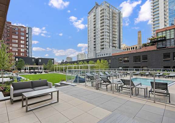 A rooftop patio with a pool and chairs.