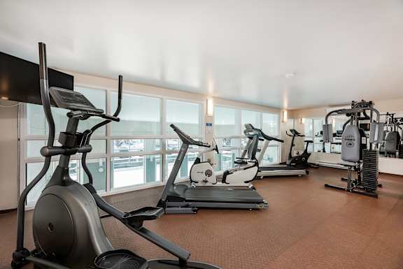 a gym with cardio machines and a view of the ocean