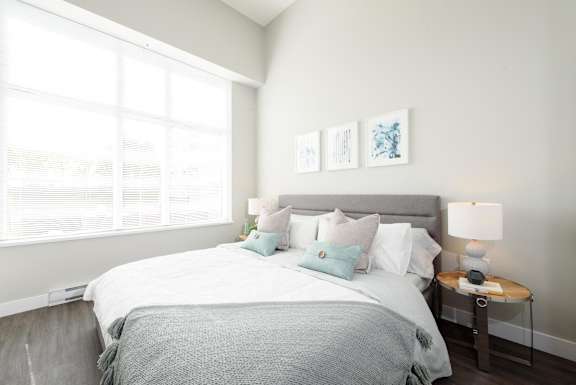 a bedroom with a large window and a bed with pillows