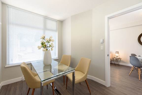 a dining room with a glass table with chairs and a vase of flowers