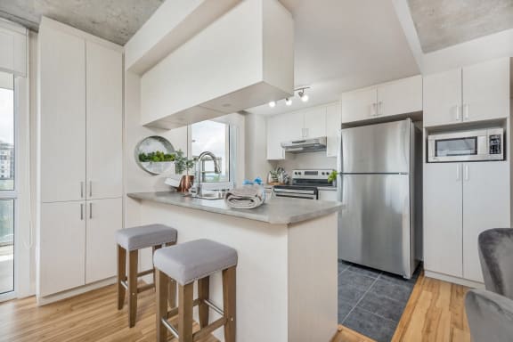 a kitchen with white cabinets and a large island with two stools