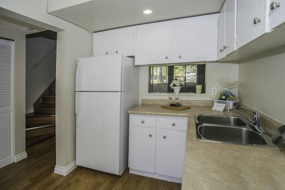 a kitchen with white cabinets and a sink and a refrigerator