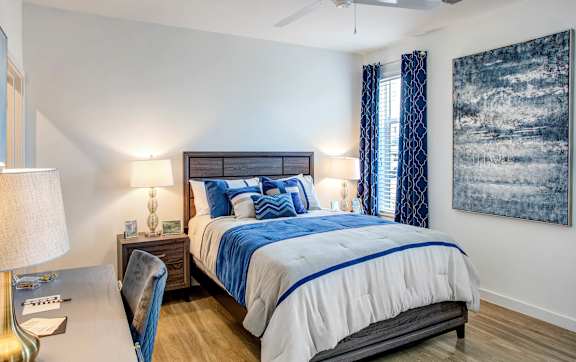 A bedroom with a large bed and a painting on the wall.