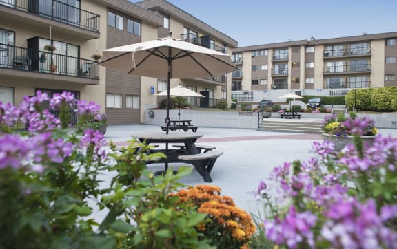 a courtyard with picnic tables and umbrellas in front of an apartment building