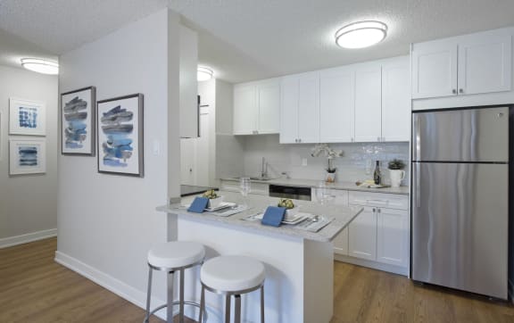 a kitchen with a bar and stools and a stainless steel refrigerator