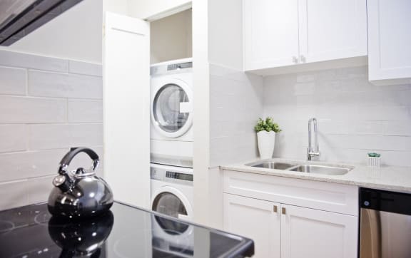 a white kitchen with a washing machine and a sink