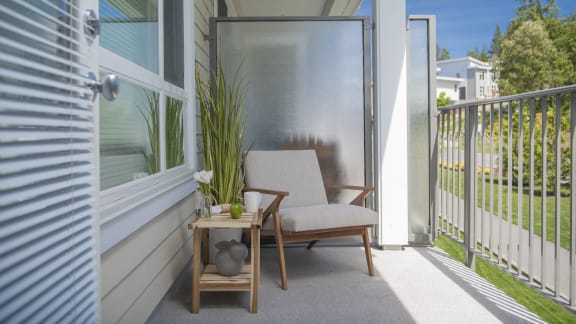 a balcony with a chair and a table with a plant