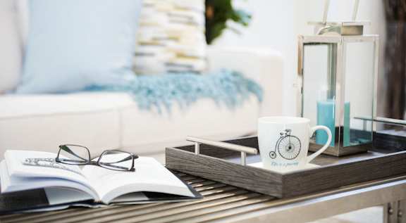 A white couch with blue pillows and a book on a coffee table.